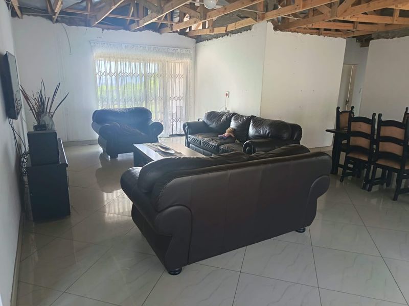 Open plan living and dining area featuring tiled floors and sliding door access, currently requiring ceiling installation and wall finishing.