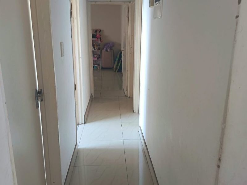 A narrow hallway featuring tiled flooring and an exposed ceiling area requiring repair and finishing to improve the overall aesthetic and structural integrity.