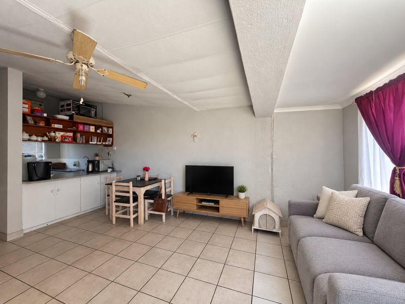 Open plan living and kitchen area featuring tiled flooring, a ceiling fan, and built-in cabinetry, offering a functional layout for daily living.