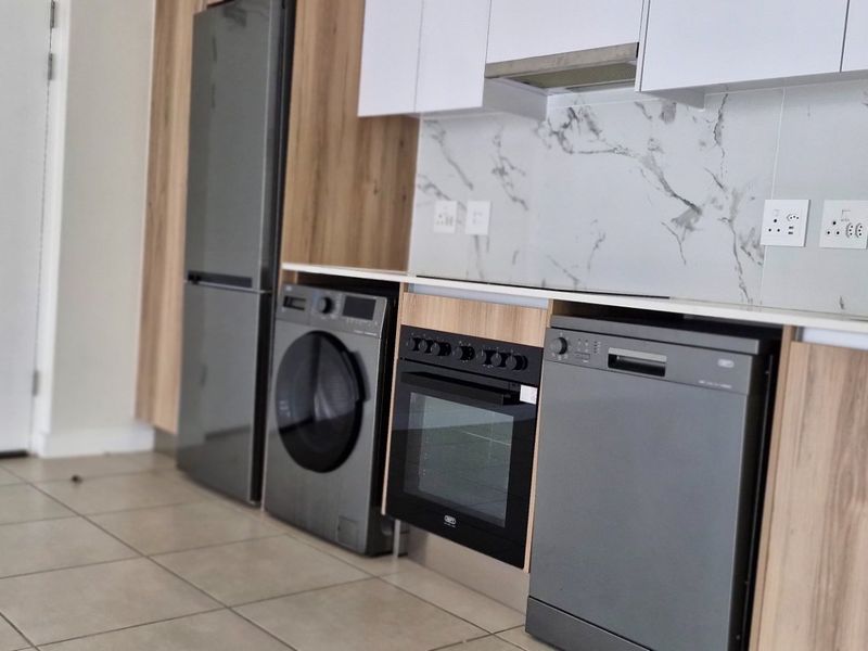 Modern kitchen featuring sleek wood-grain and white cabinetry, marble-look splashback, and integrated appliances including an oven and extractor fan.