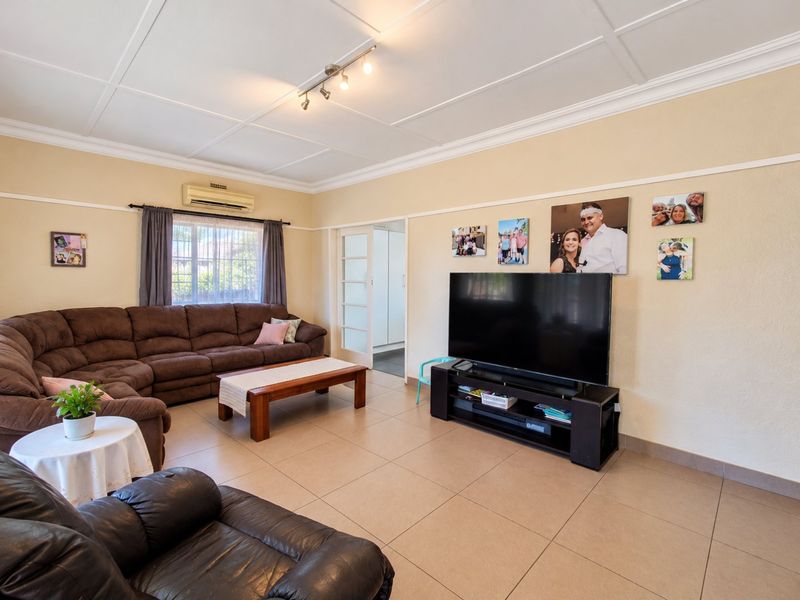 Spacious living room featuring tiled flooring, a wall-mounted air conditioning unit, and classic ceiling panel detailing.