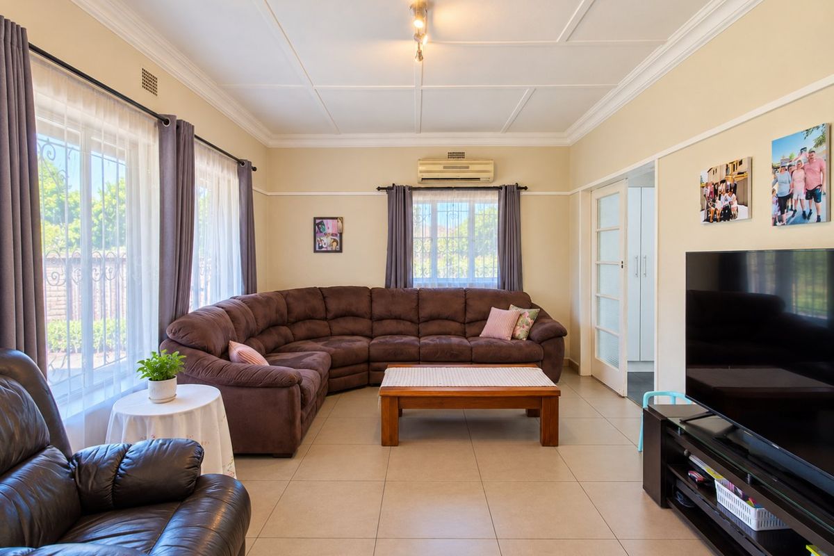 A well-maintained living room featuring tiled flooring, decorative ceiling molding, and a wall-mounted air conditioning unit, offering a comfortable and functional living space.