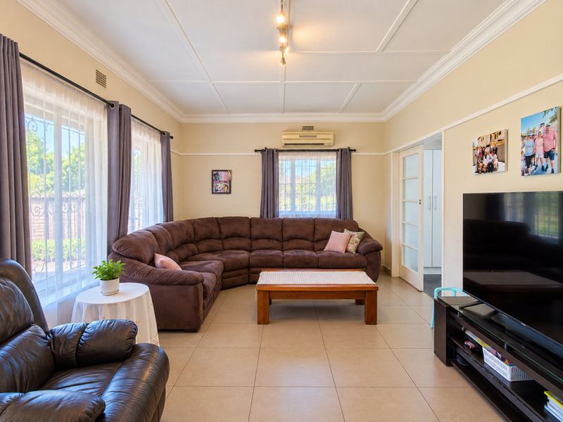 A well-maintained living room featuring tiled flooring, decorative ceiling molding, and a wall-mounted air conditioning unit, offering a comfortable and functional living space.
