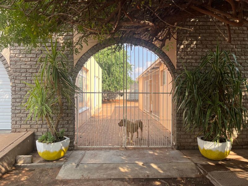 A gated entrance featuring a brick arched gateway leading to a paved driveway and side access path.