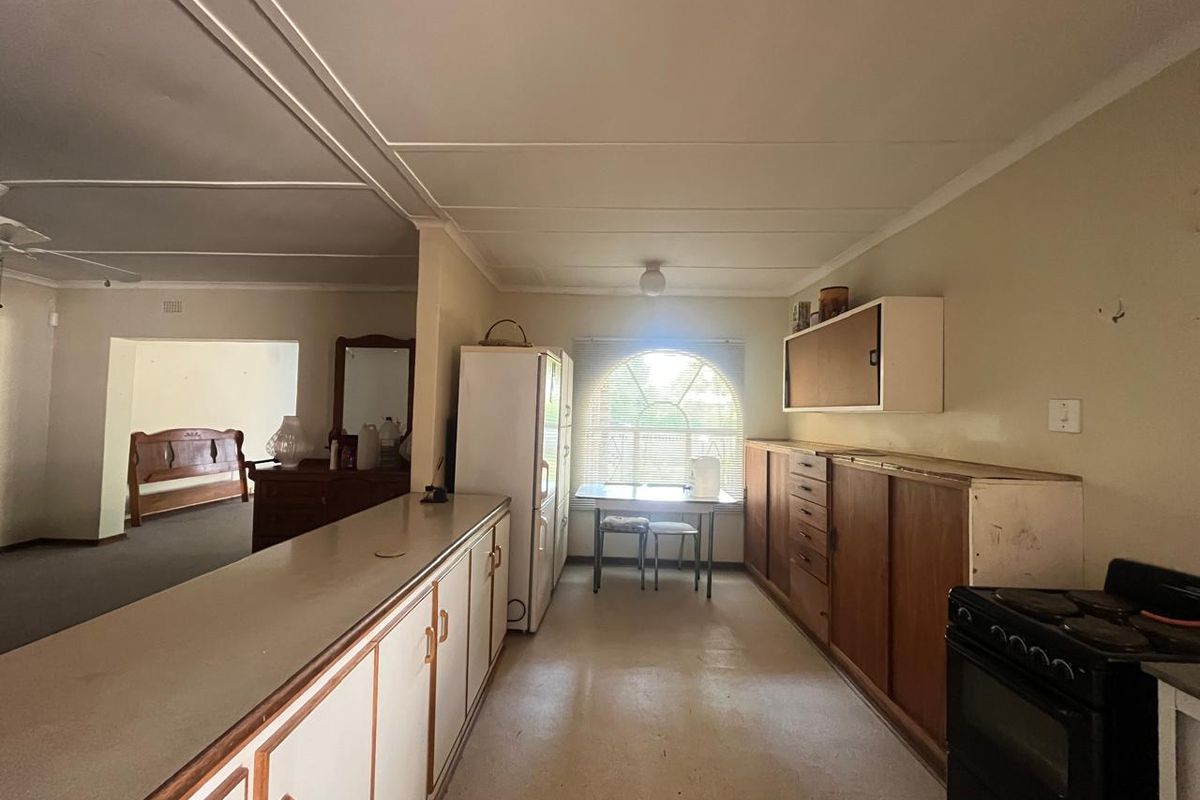 A dated kitchen featuring original cabinetry, laminate countertops, and a freestanding stove, offering significant potential for a modern renovation and layout update.