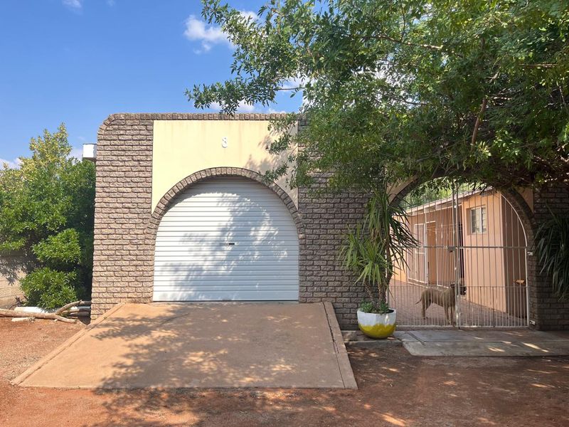 Exterior view of a single garage featuring a roll-up door, arched brick detailing, and a concrete driveway entrance.