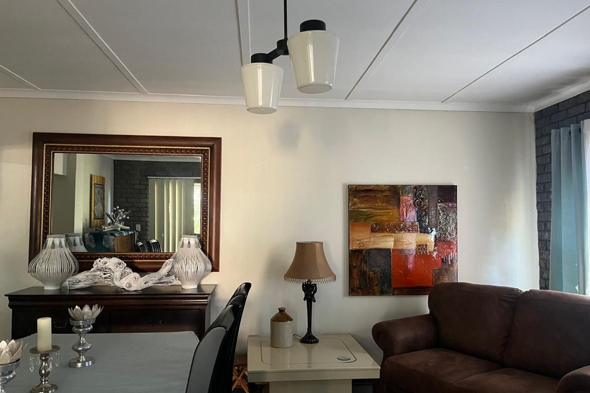 A living room area featuring an exposed brick wall and a central pendant light fixture, providing a functional space for relaxation.