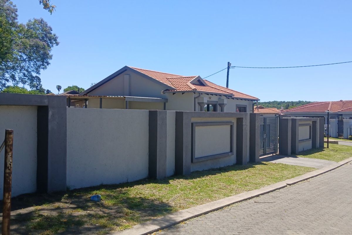 A view of the property's front exterior, featuring a modern perimeter wall, gated entrance, and tiled roof house structure.