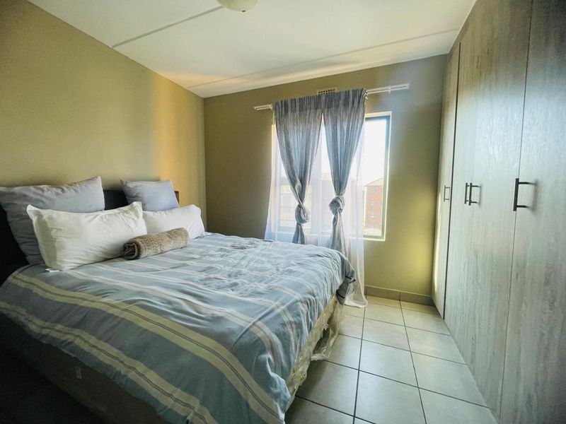 A functional bedroom featuring built-in cupboards, tiled flooring, and natural light from the window.