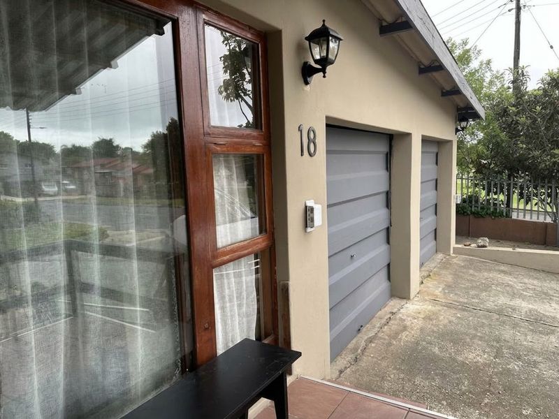 Front exterior view of the property featuring a double garage, timber-framed windows, and a concrete driveway.