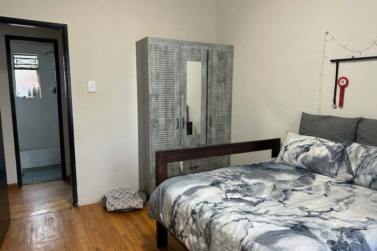 A bedroom featuring hardwood flooring and direct access to an adjoining bathroom.