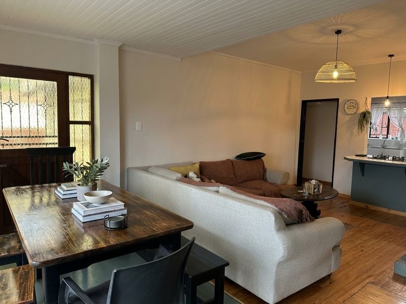Open plan living and dining area featuring warm timber flooring, a beaded timber ceiling, and a breakfast bar connecting to the kitchen.