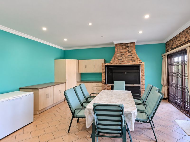 Covered patio area featuring a built-in brick fireplace, tiled flooring, and integrated cabinetry, providing a functional space for indoor-outdoor entertaining.