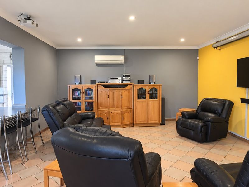 Spacious open-plan living area featuring a modern kitchen with subway tile backsplash, tiled flooring, and integrated entertainment setup with projector and screen.