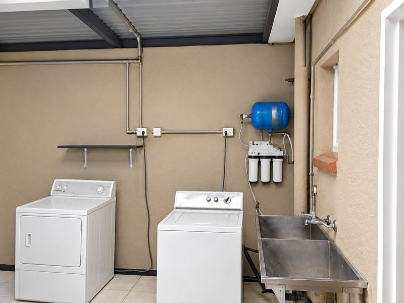 Functional laundry area featuring a stainless steel double sink, water filtration system, and dedicated space for laundry appliances.