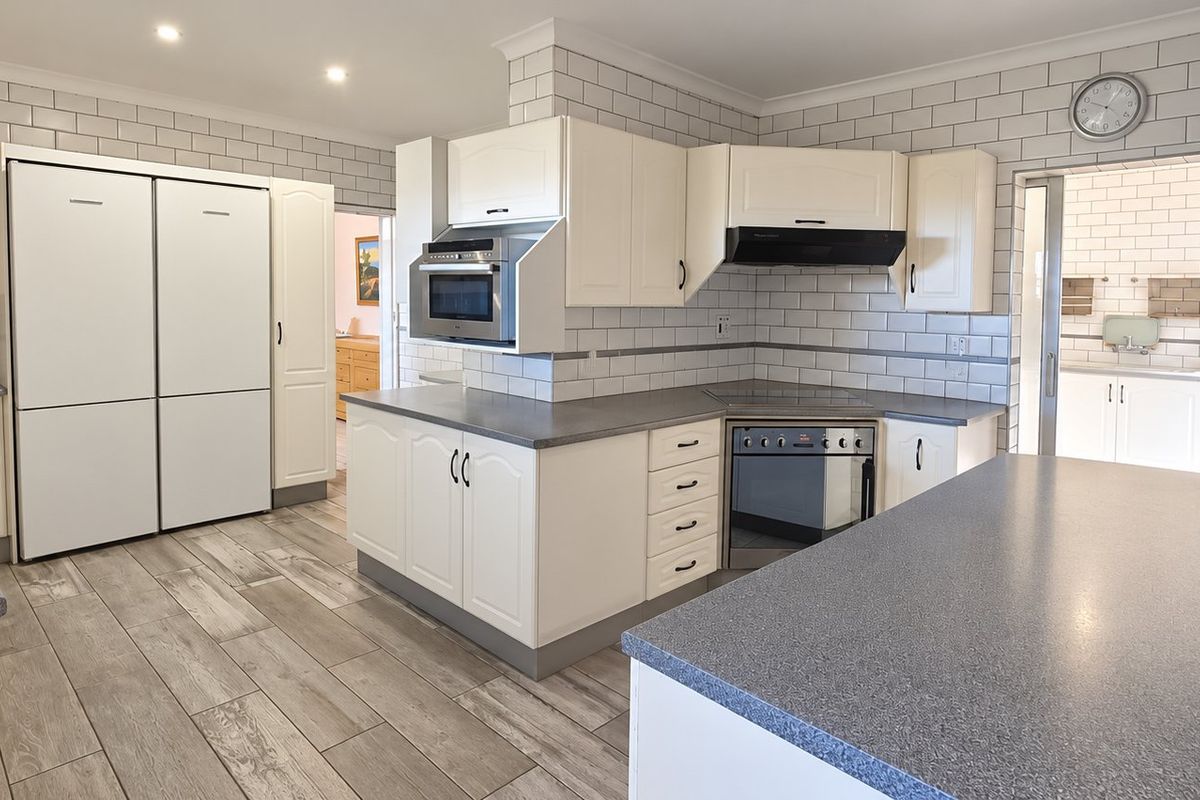 A well-maintained kitchen featuring white cabinetry, subway tile backsplash, stone-look laminate countertops, and integrated appliances with a functional layout.