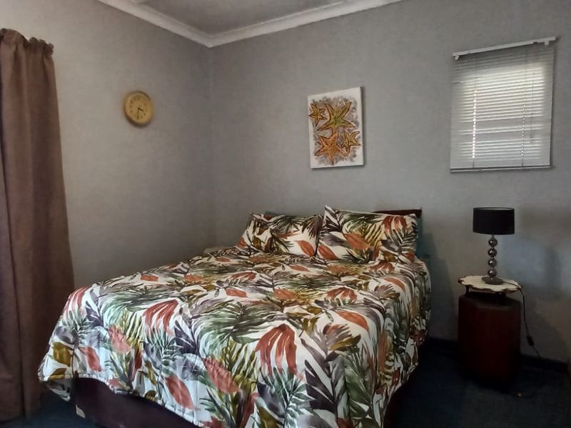A standard bedroom featuring neutral wall paint, coving, and window treatments including venetian blinds and curtain rails.