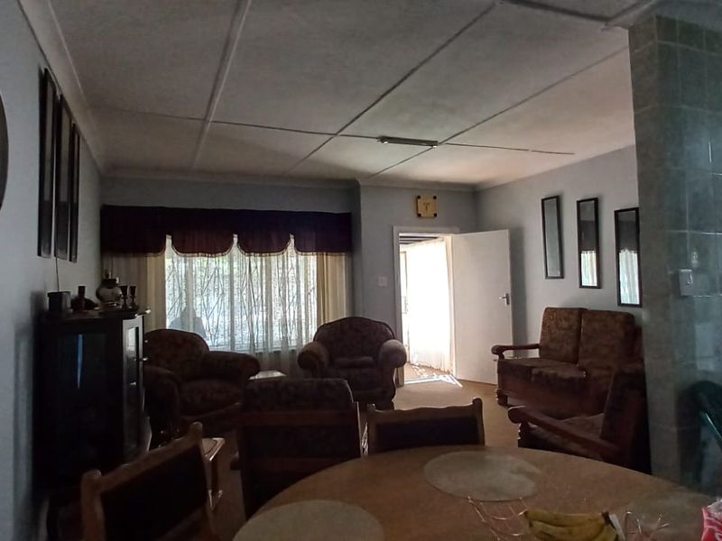 Open plan living and dining area featuring tiled wall accents and traditional ceiling panels, offering a functional layout with potential for modern updates.