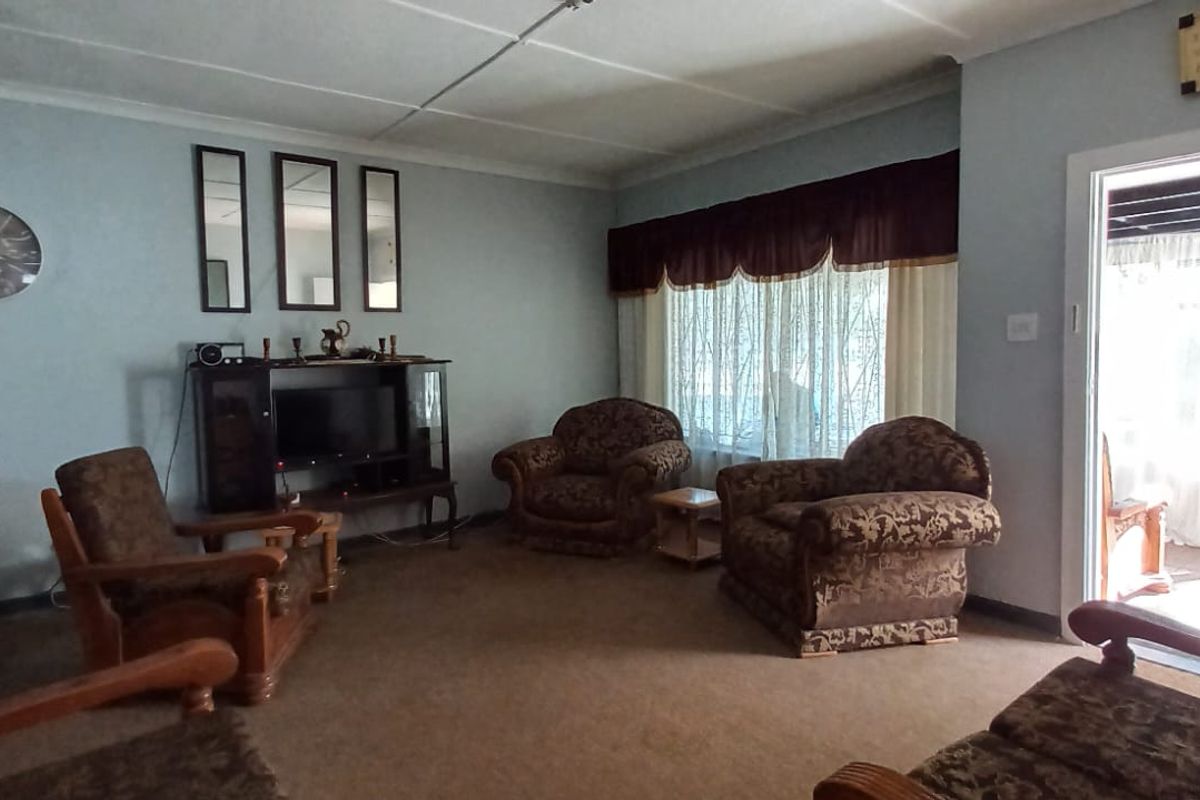 A spacious living room featuring carpeted flooring, ceiling coving, and a sliding door providing access to the outdoor area.