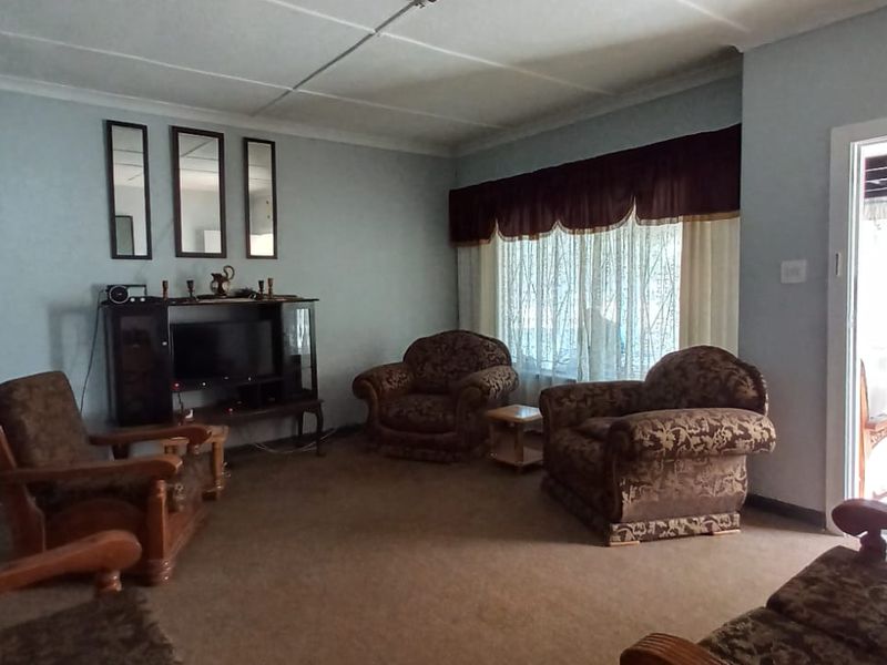 A spacious living room featuring carpeted flooring, ceiling coving, and a sliding door providing access to the outdoor area.