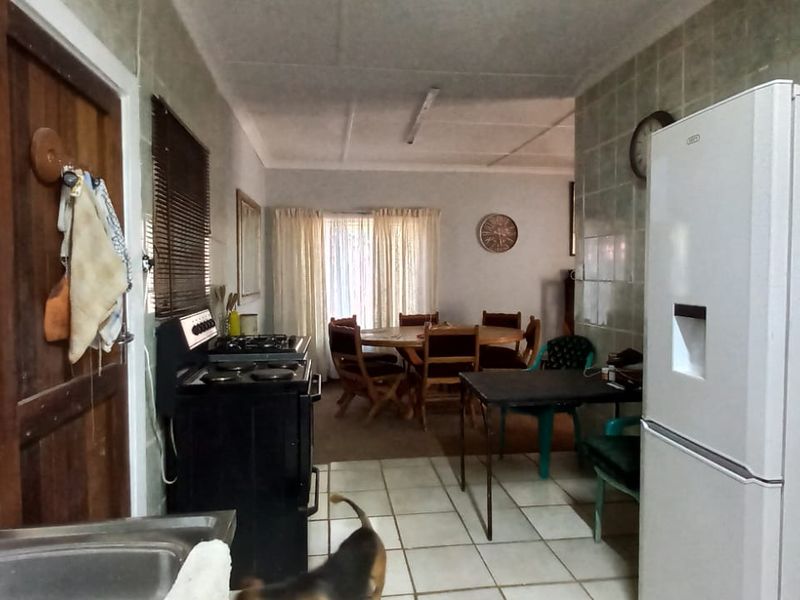 Open plan kitchen and dining area featuring tiled flooring and walls, providing a functional space with potential for modern updates.