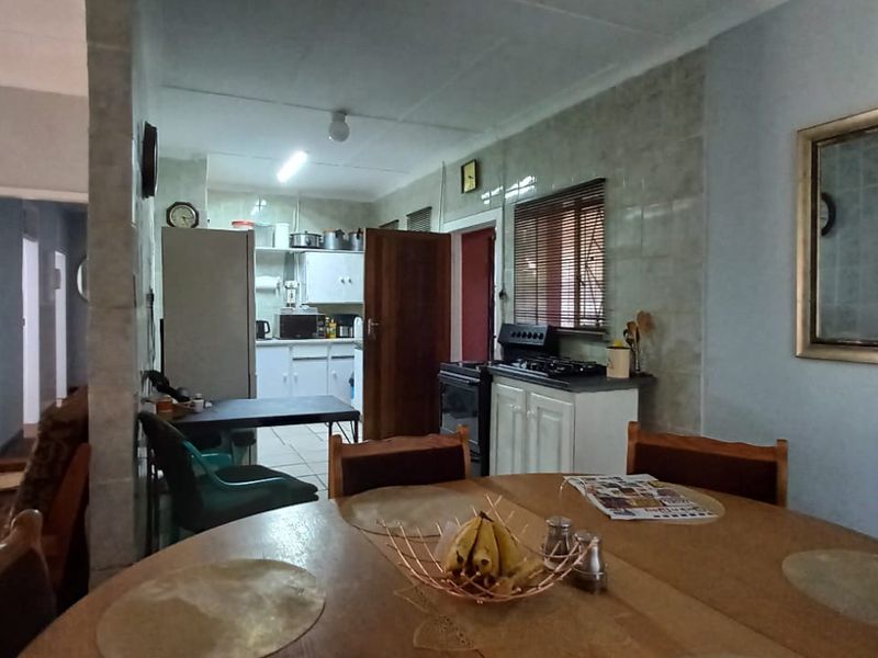 Open plan living and dining area featuring a functional kitchen with built-in cabinetry and tiled splashbacks, offering a practical layout for daily living.