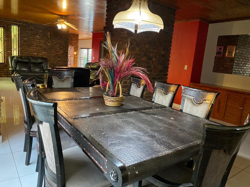 Dining room featuring exposed brick walls, timber ceiling paneling, and a central pendant light fixture.
