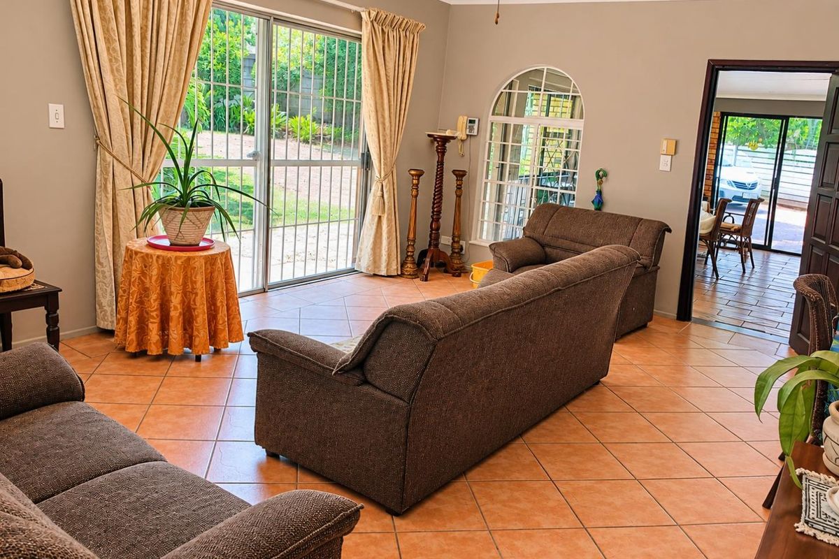 Spacious living room featuring ceramic tile flooring, an arched window, and large sliding glass doors providing access to the garden area.