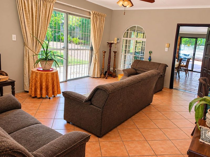 Spacious living room featuring ceramic tile flooring, an arched window, and large sliding glass doors providing access to the garden area.