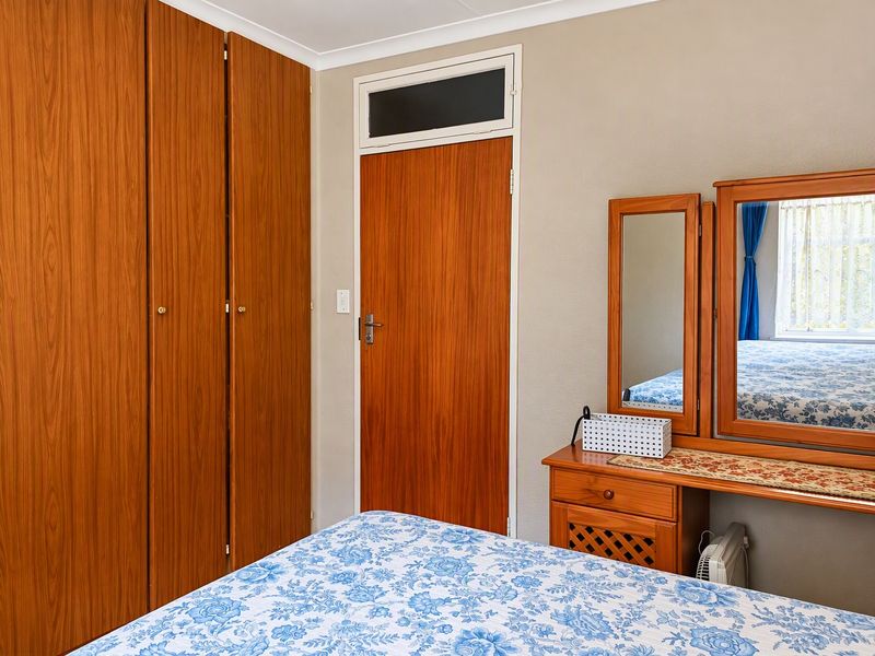 A bedroom featuring built-in wooden cupboards and a classic internal door with a transom window, offering a functional and traditional layout.