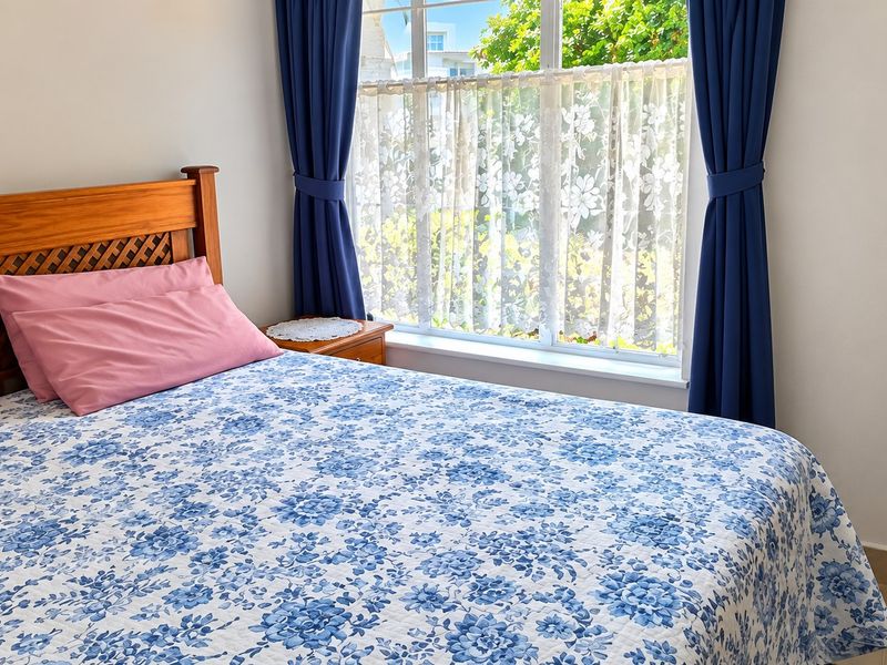 A bright bedroom featuring tiled flooring and a large window that allows for natural light.