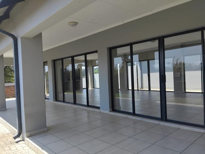 A spacious covered patio featuring neutral tiled flooring and large sliding glass doors that provide seamless access to the interior living area.
