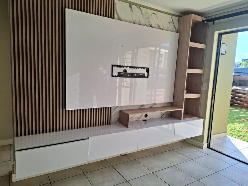 Modern living room featuring a custom built-in media wall with slatted timber accents, marble-effect paneling, and sleek floating cabinetry.