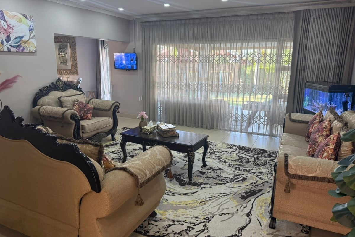 Spacious living room featuring tiled flooring, recessed ceiling lighting, and large sliding glass doors with security gates providing access to the outdoor area.
