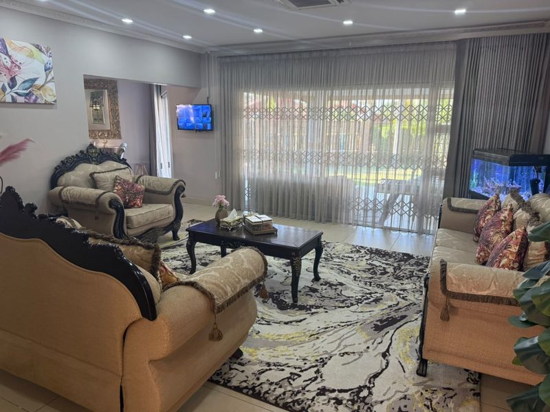 Spacious living room featuring tiled flooring, recessed ceiling lighting, and large sliding glass doors with security gates providing access to the outdoor area.