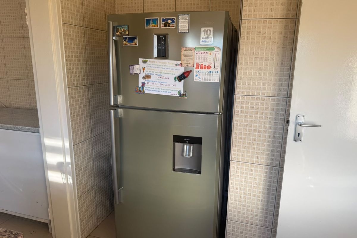 A kitchen area featuring tiled walls and flooring, providing a functional space for food preparation and storage.
