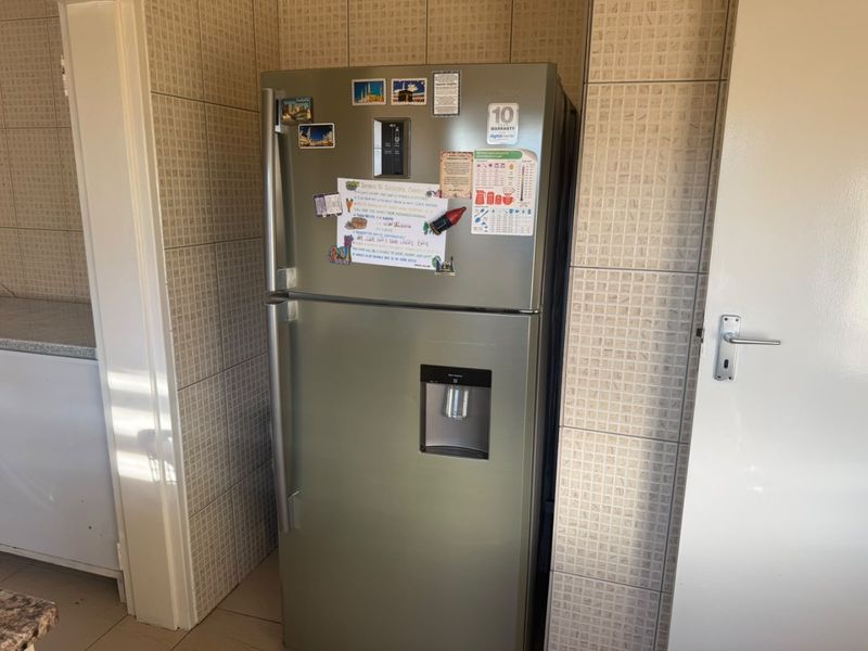 A kitchen area featuring tiled walls and flooring, providing a functional space for food preparation and storage.
