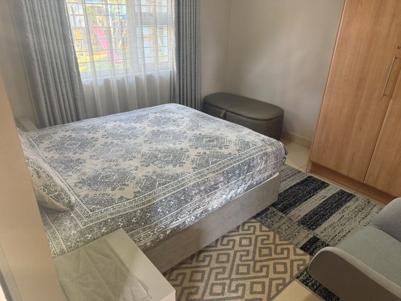 A well-maintained bedroom featuring tiled flooring, a built-in wardrobe, and a window with security bars, offering a clean and functional living space.