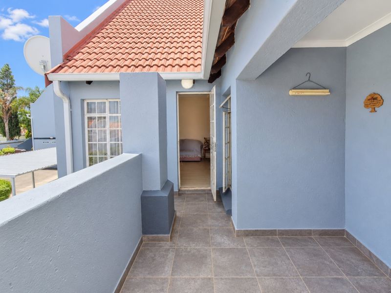A covered balcony featuring tiled flooring and access to the interior through a french door, set against a blue exterior wall.