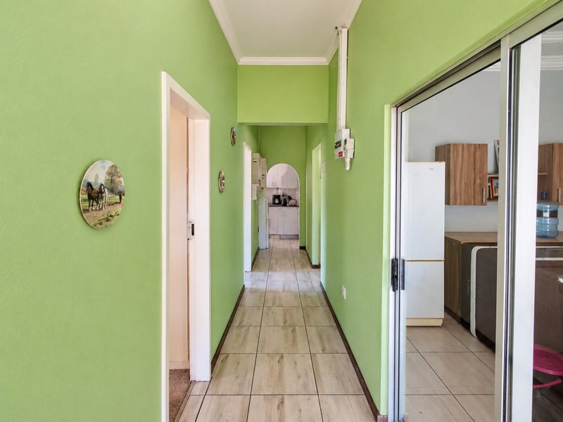 A bright hallway featuring tiled flooring, an arched transition to the kitchen area, and a sliding glass door leading to an adjacent room.
