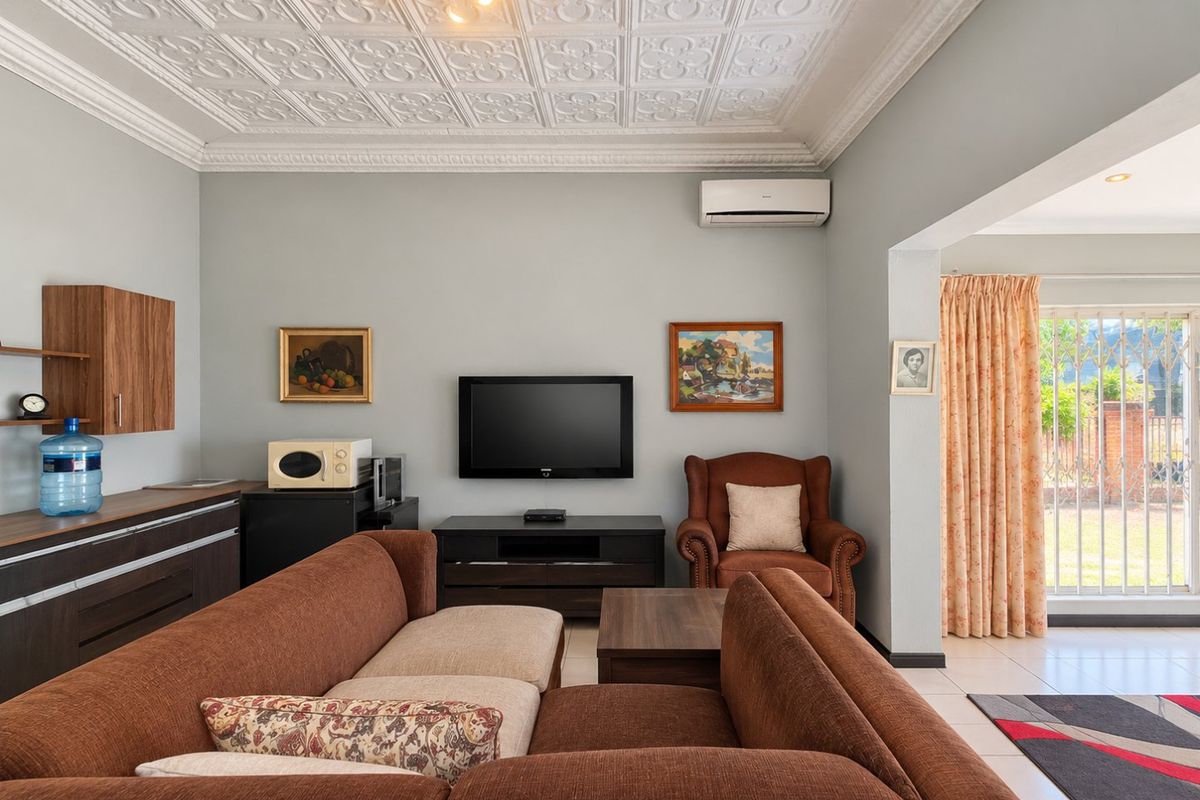 A comfortable living room featuring a decorative pressed metal ceiling, split-system air conditioning, built-in cabinetry, and direct access to the outdoor area.
