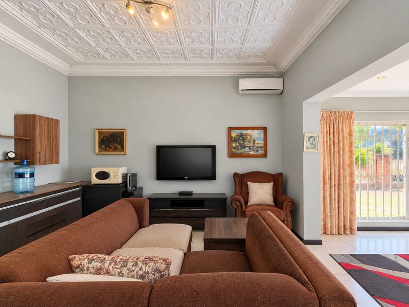 A comfortable living room featuring a decorative pressed metal ceiling, split-system air conditioning, built-in cabinetry, and direct access to the outdoor area.
