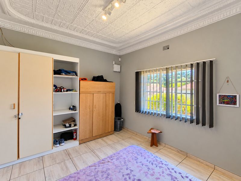 Bedroom featuring tiled flooring, built-in cupboards, and a decorative pressed metal ceiling with integrated lighting.