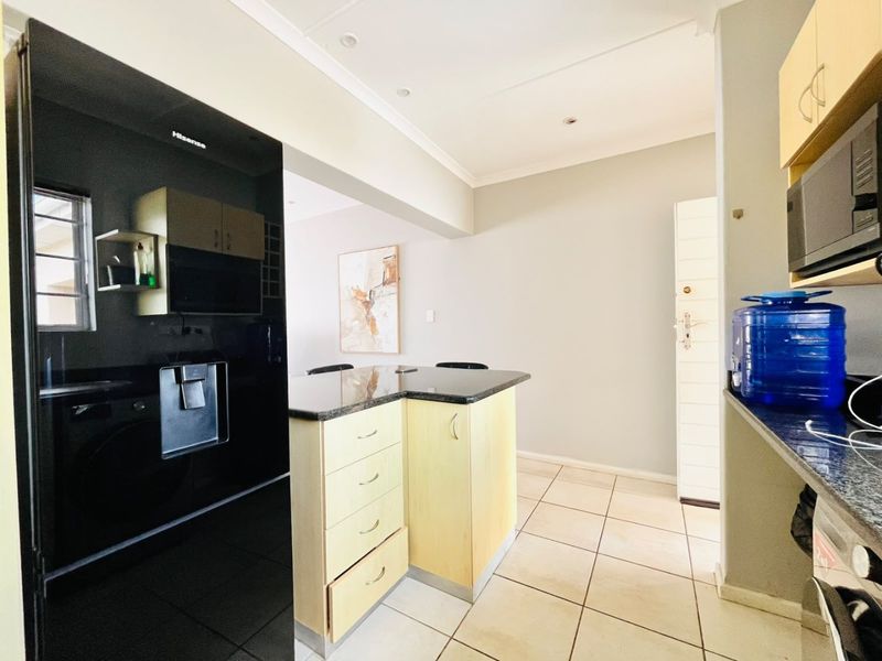 A functional kitchen featuring granite countertops, light wood cabinetry, and tiled flooring, offering a clean and practical layout for daily meal preparation.