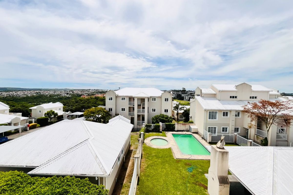 Aerial view of the apartment complex featuring a communal swimming pool, plunge pool, landscaped garden areas, and well-maintained building exteriors with metal roofing.