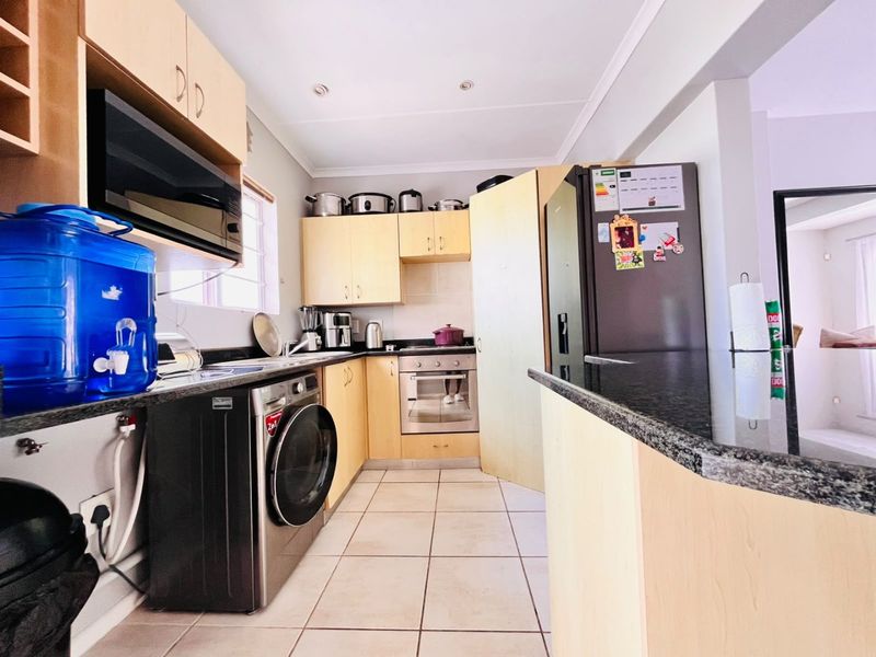 A functional kitchen featuring light wood cabinetry, granite countertops, built-in oven, and tiled flooring, offering a practical layout for daily meal preparation.