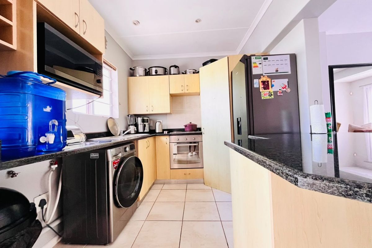 A functional kitchen featuring light wood cabinetry, granite countertops, built-in oven, and tiled flooring, offering a practical layout for daily meal preparation.