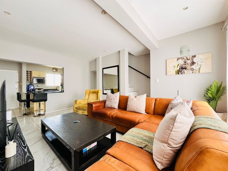 Spacious open-plan living area featuring polished marble-look floor tiles, recessed lighting, and a convenient breakfast bar connecting to the kitchen.