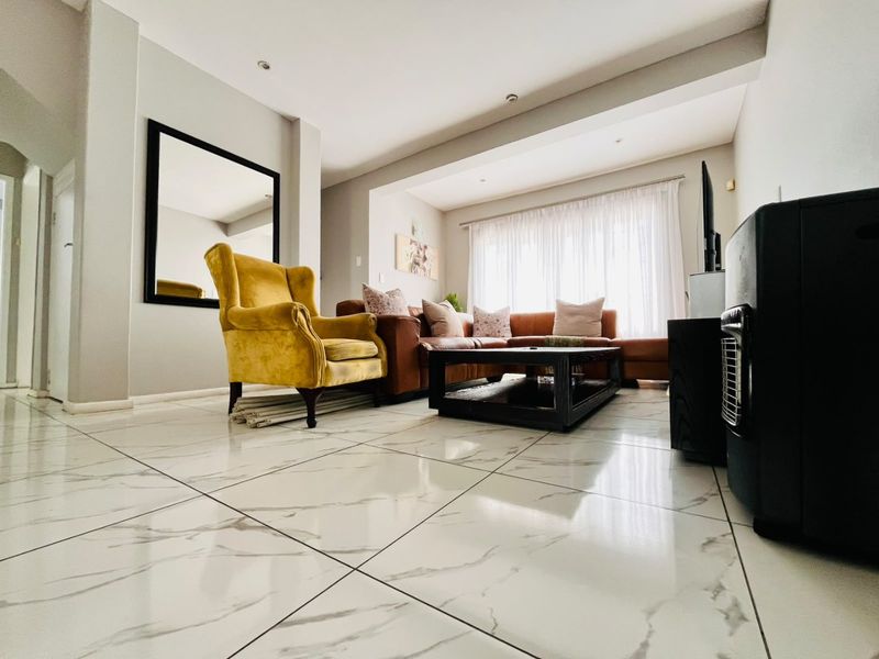 A bright living room featuring polished marble-look floor tiles, recessed downlighting, and a modern bulkhead ceiling design.