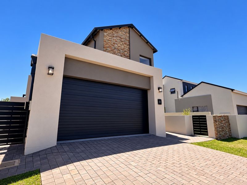Modern double-storey residential property featuring a paved driveway, secure double garage, and contemporary stone-clad architectural detailing.